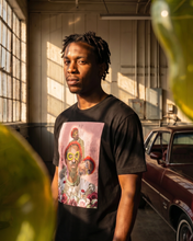 Load image into Gallery viewer, Man wearing a black t-shirt with a colorful graphic design, standing in a sunlit indoor setting.